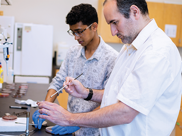 A student works with male professor in a lab.